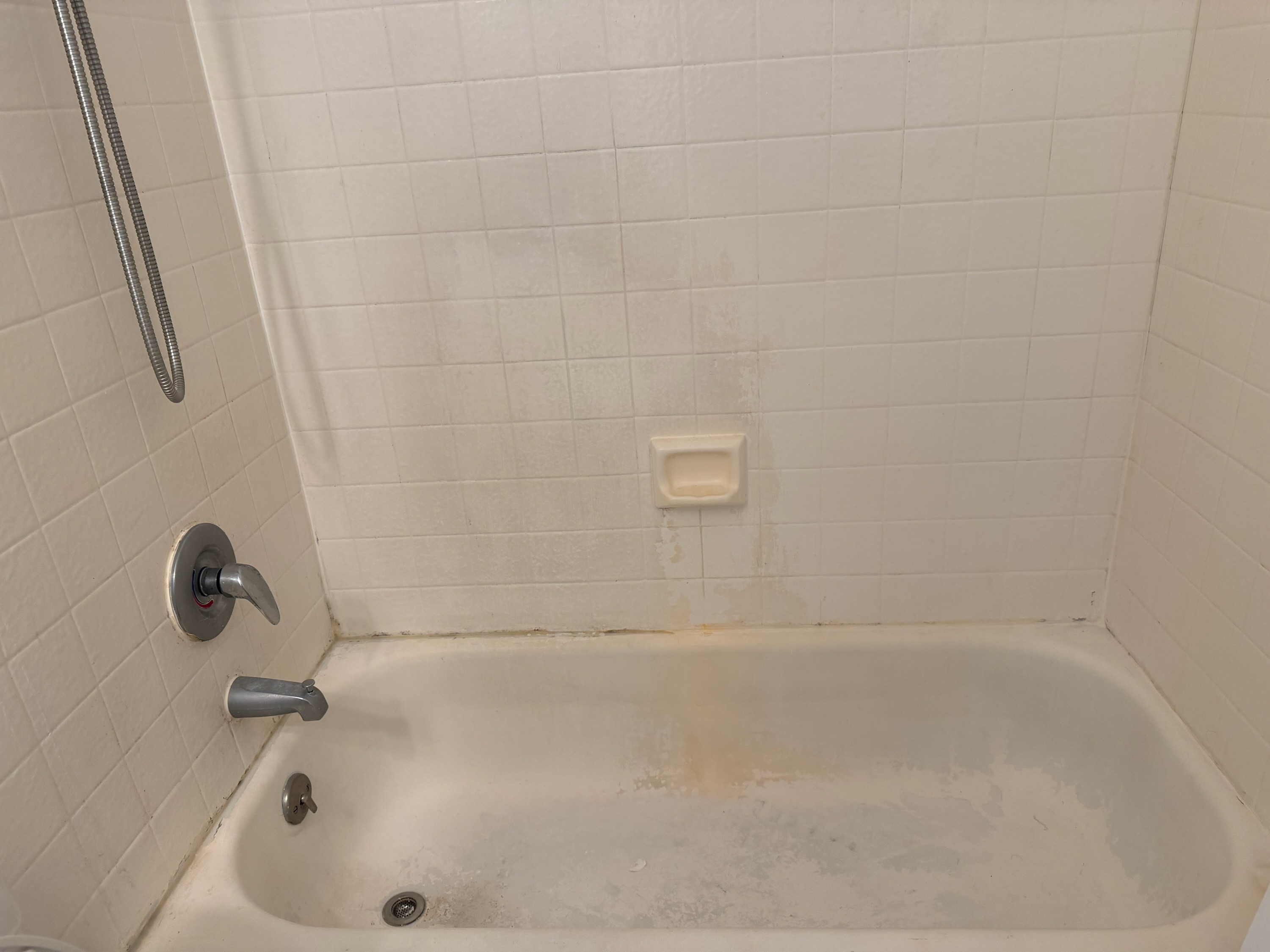 Stained bathroom tile with rust marks and yellowing - common tile problem fixed by reglazing