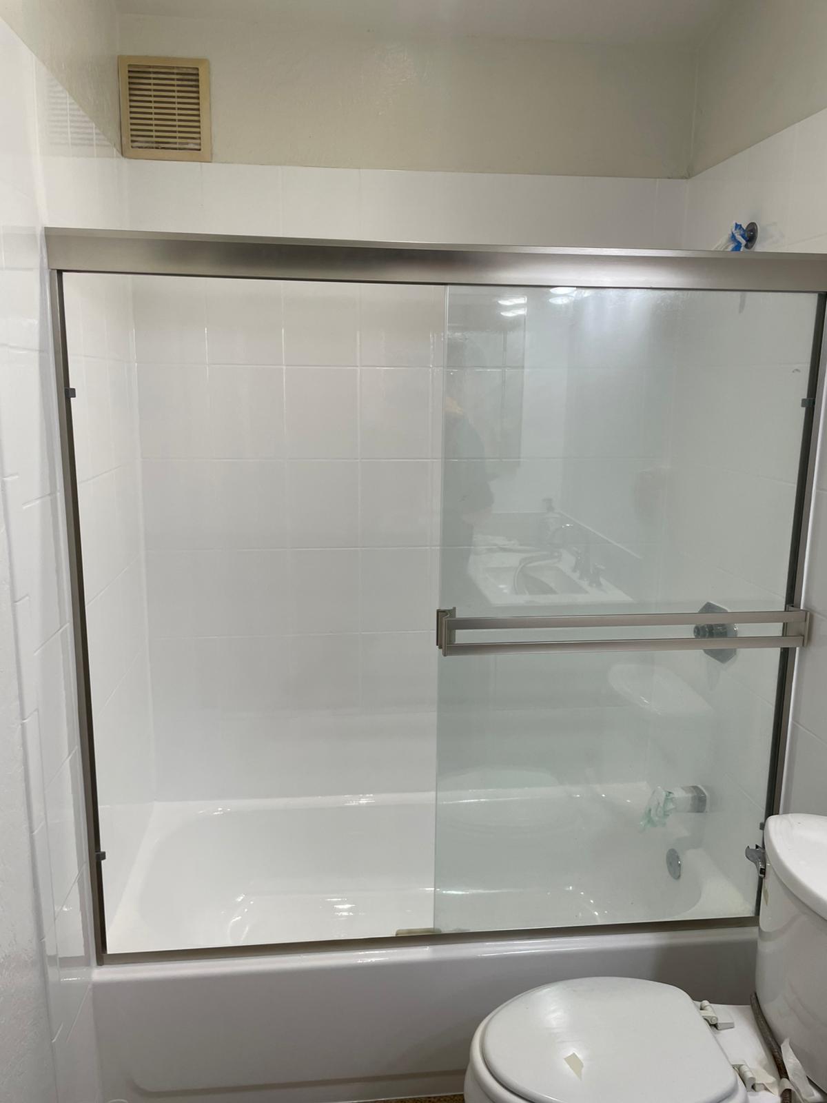 Same bathroom after refinishing: bright white tile and tub