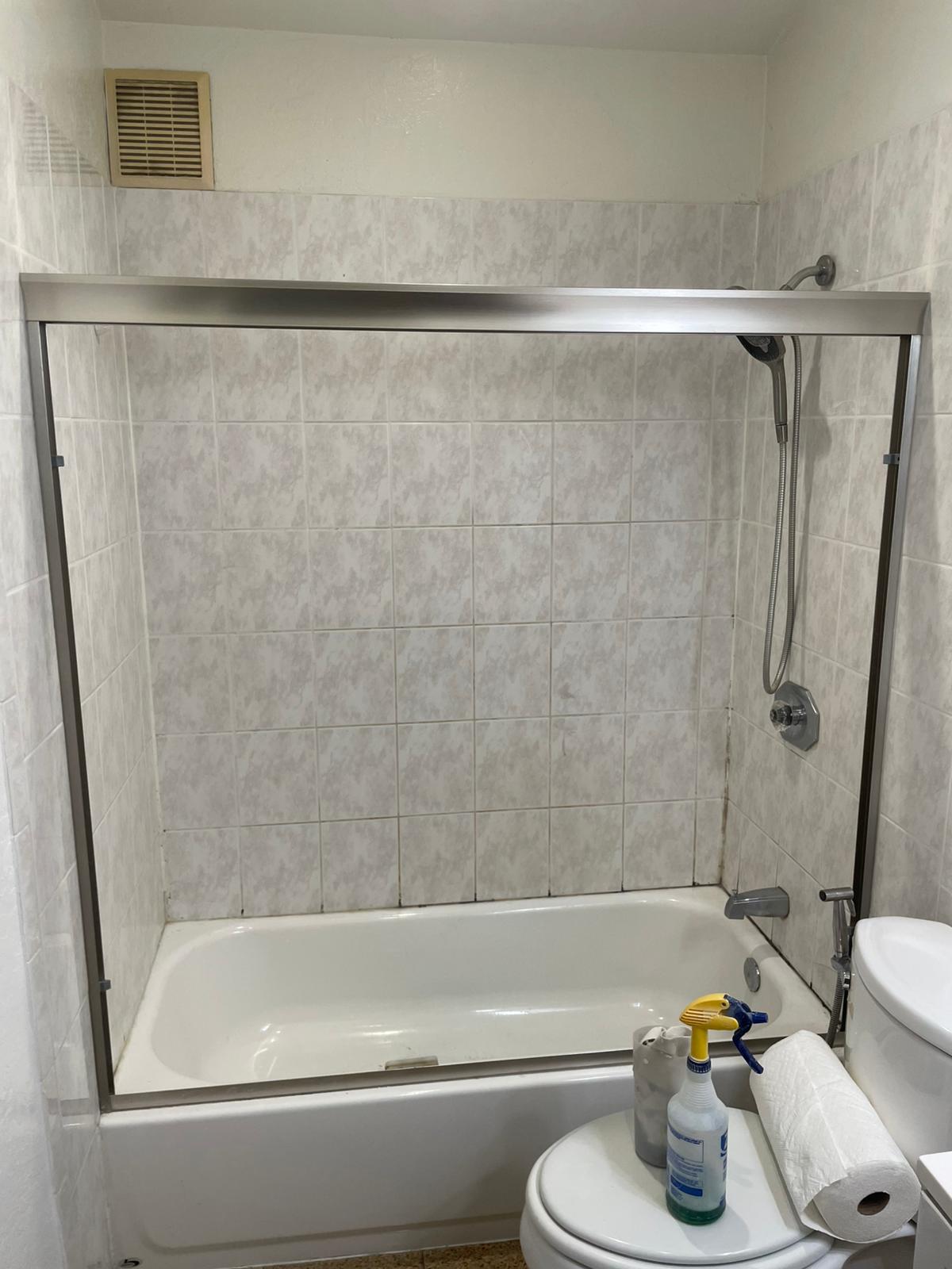 Bathroom before refinishing: dated beige marbled tile and a worn tub